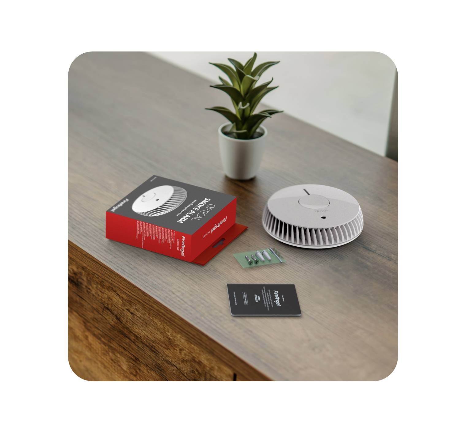 A smoke detector lies beside its packaging and instruction manual on a wooden table. A small plant is positioned nearby.