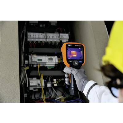 A person is using a thermal imaging camera to check the temperature of an electrical control cabinet.