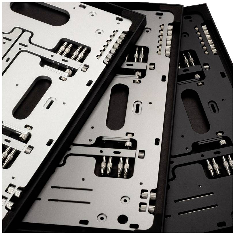 Three empty computer cases in black, silver, and space grey, lying side by side, display various metal plates and screws.