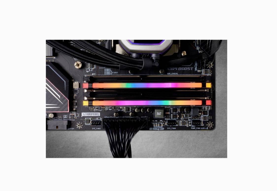 A computer motherboard with installed RGB RAM modules, emitting colourful lights in various colours.