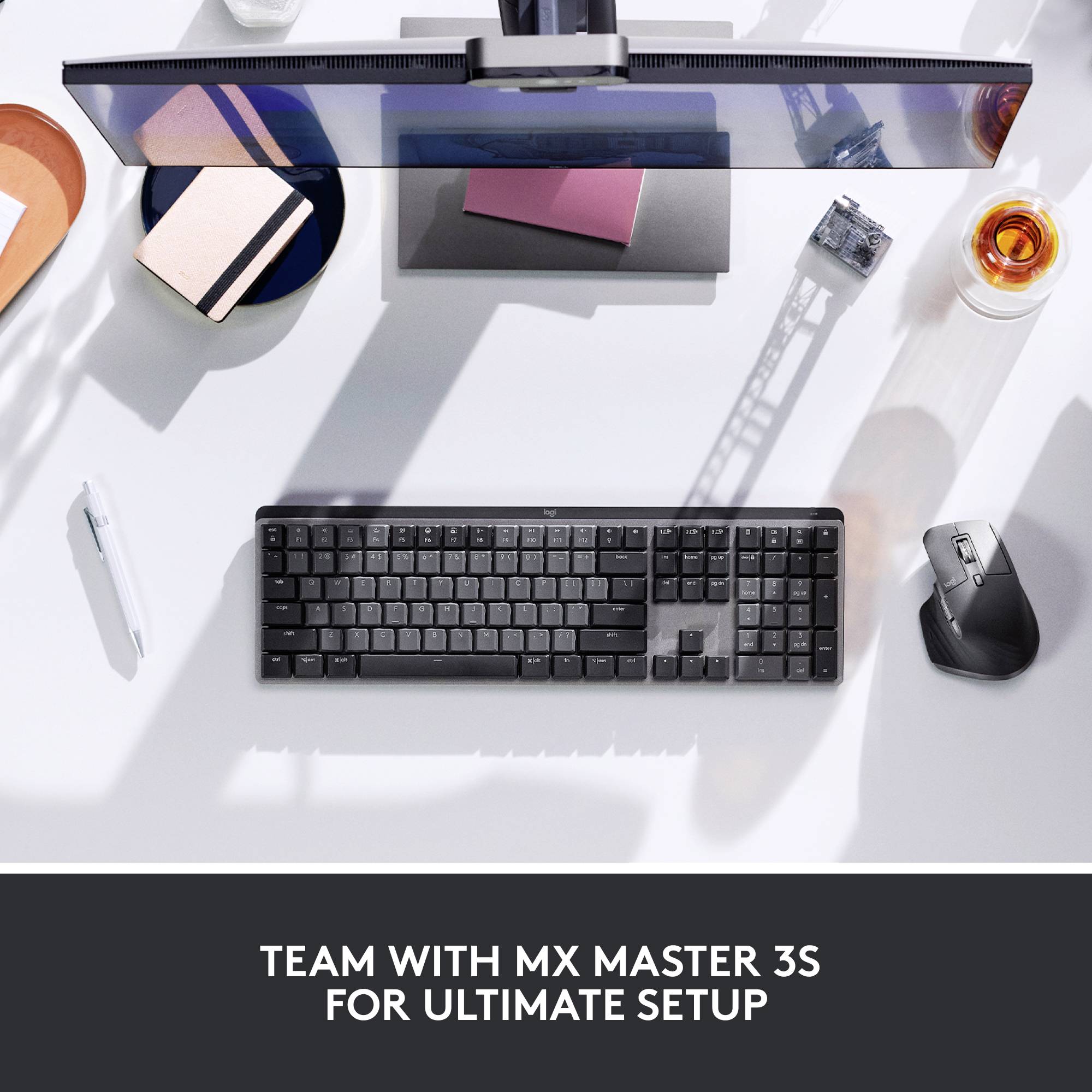 A stylish office environment from above: keyboard, mouse, pen and drink on a table. Text: 'The ultimate setup with MX Master 3S'.