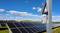Solar installation on a field beneath a blue sky. A camera on a post is in the foreground.