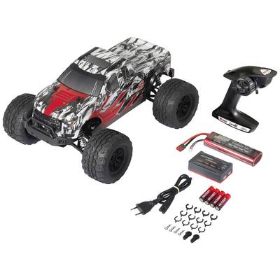 A remote-controlled car with accessories: remote control, charger, rechargeable batteries, and batteries. The car has a red and black camouflage design.