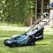 A person is mowing a green lawn with a blue lawnmower in front of a house.