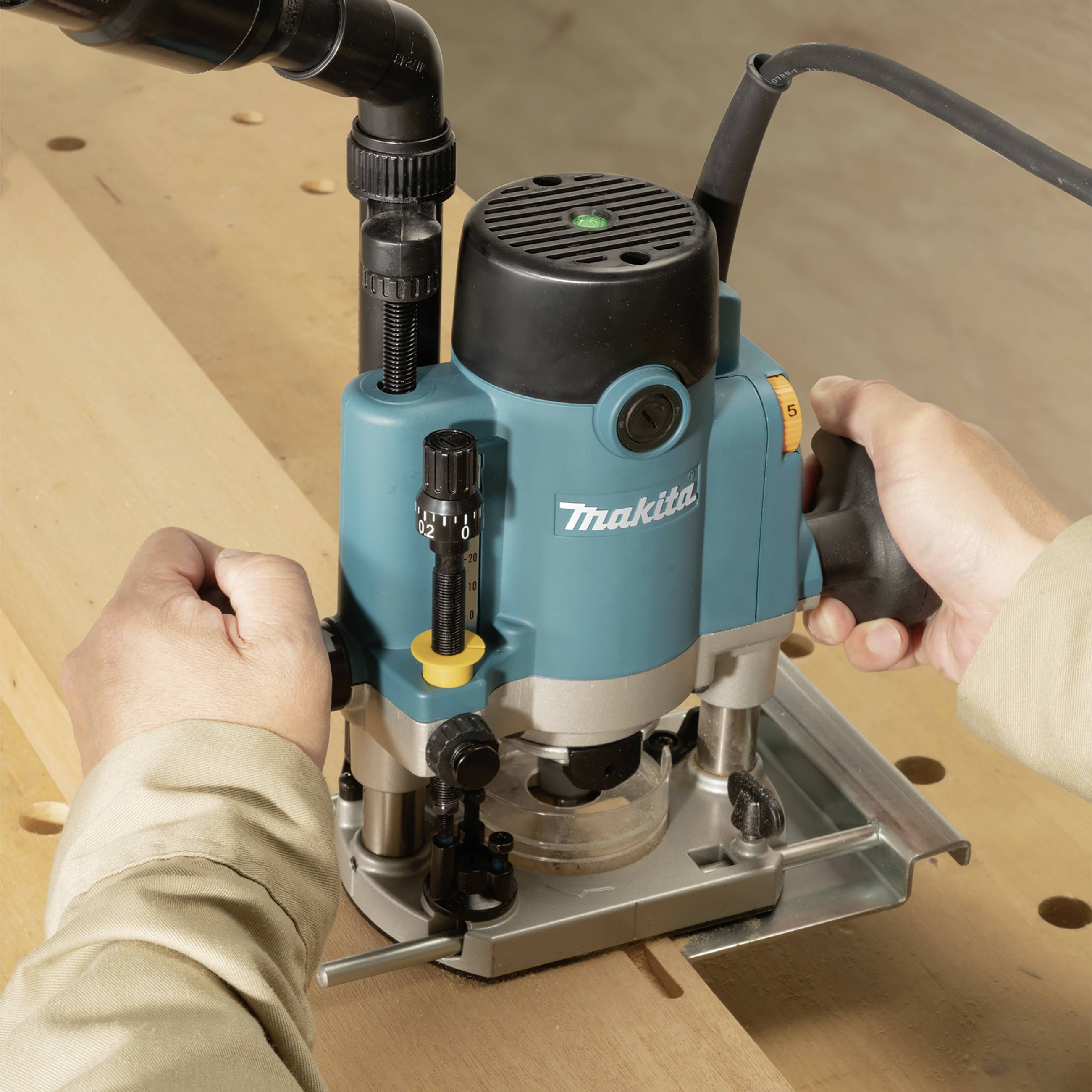 A person is using a blue milling machine on a wooden board, focusing on precision work in woodworking.