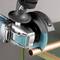 An electric angle grinder is cutting a copper pipe on a green table. The tool has a blue protective cover.