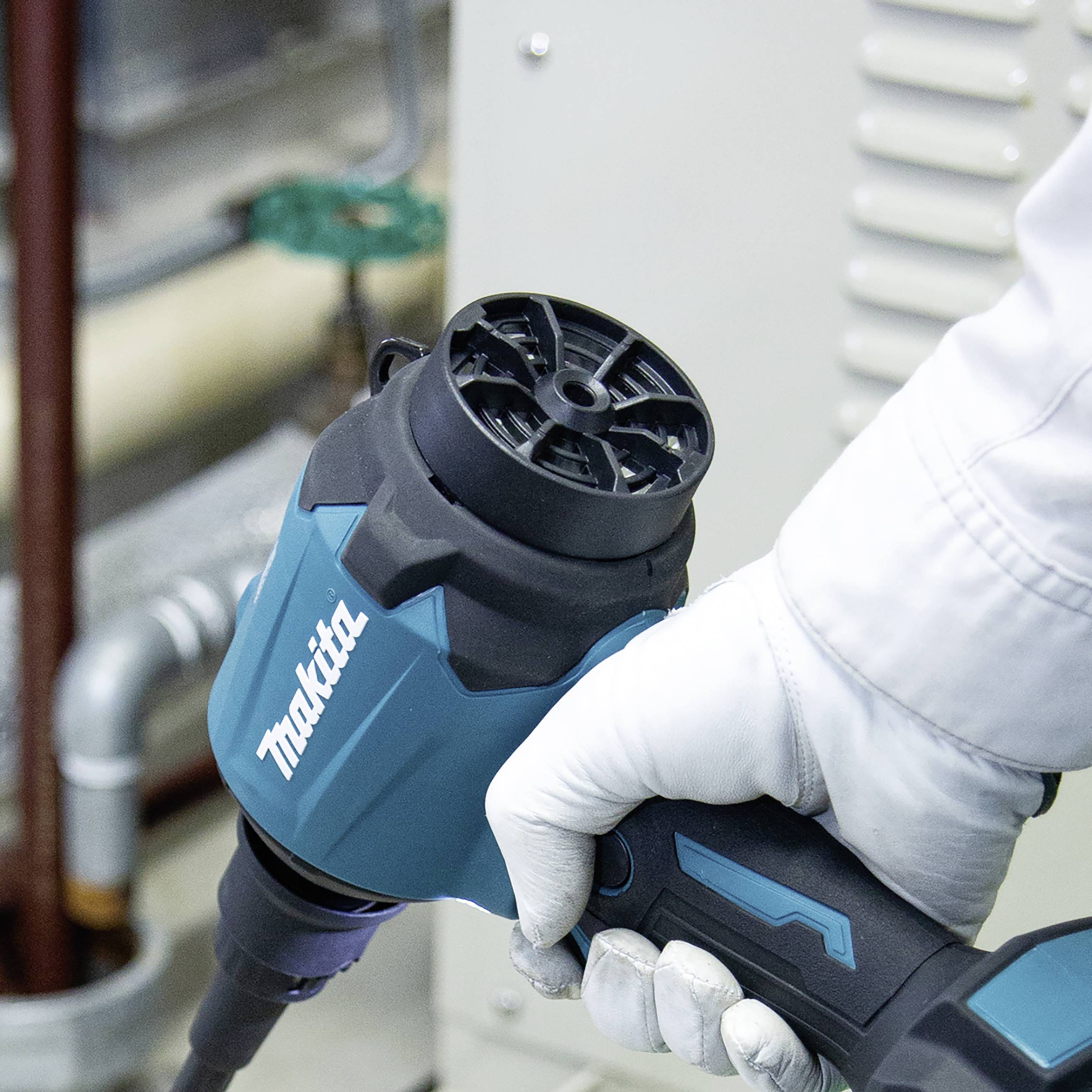 A hand is holding a blue-black electric tool with a 'Makita' logo, against a metallic background.