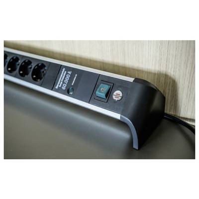 Close-up of a power strip on a desk, showing the on/off switch and connected outlets with a plugged-in cable.<br>