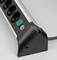 A black power strip with five sockets and a green on/off switch against a grey background.