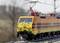 A yellow-orange train travels on rails, surrounded by a blurred landscape background. The train bears the 'PKP Cargo' logo.