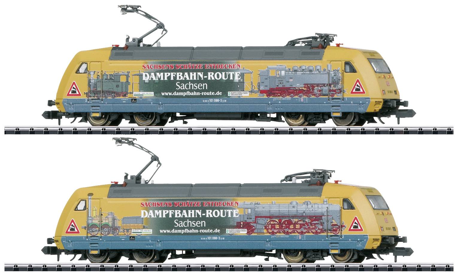 Two model steam railway locomotives from the Saxony Steam Railway Route in yellow and blue with decorative graphics, standing on tracks.
