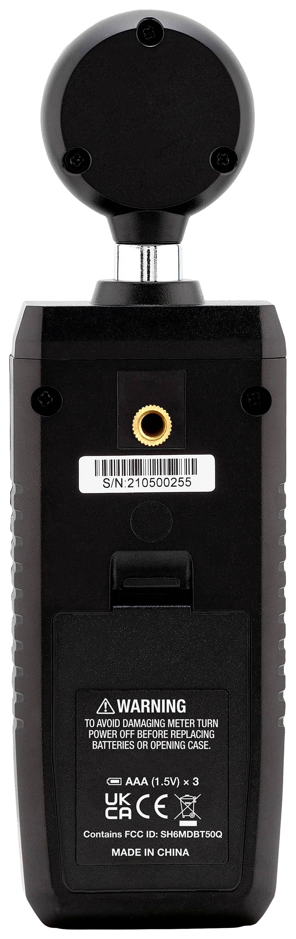 Handheld measuring device viewed from the rear, showing battery compartment, warning notices, serial number, and connections.