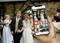 A person is holding a smartphone with a photography app, with a wedding couple and guests in the background.