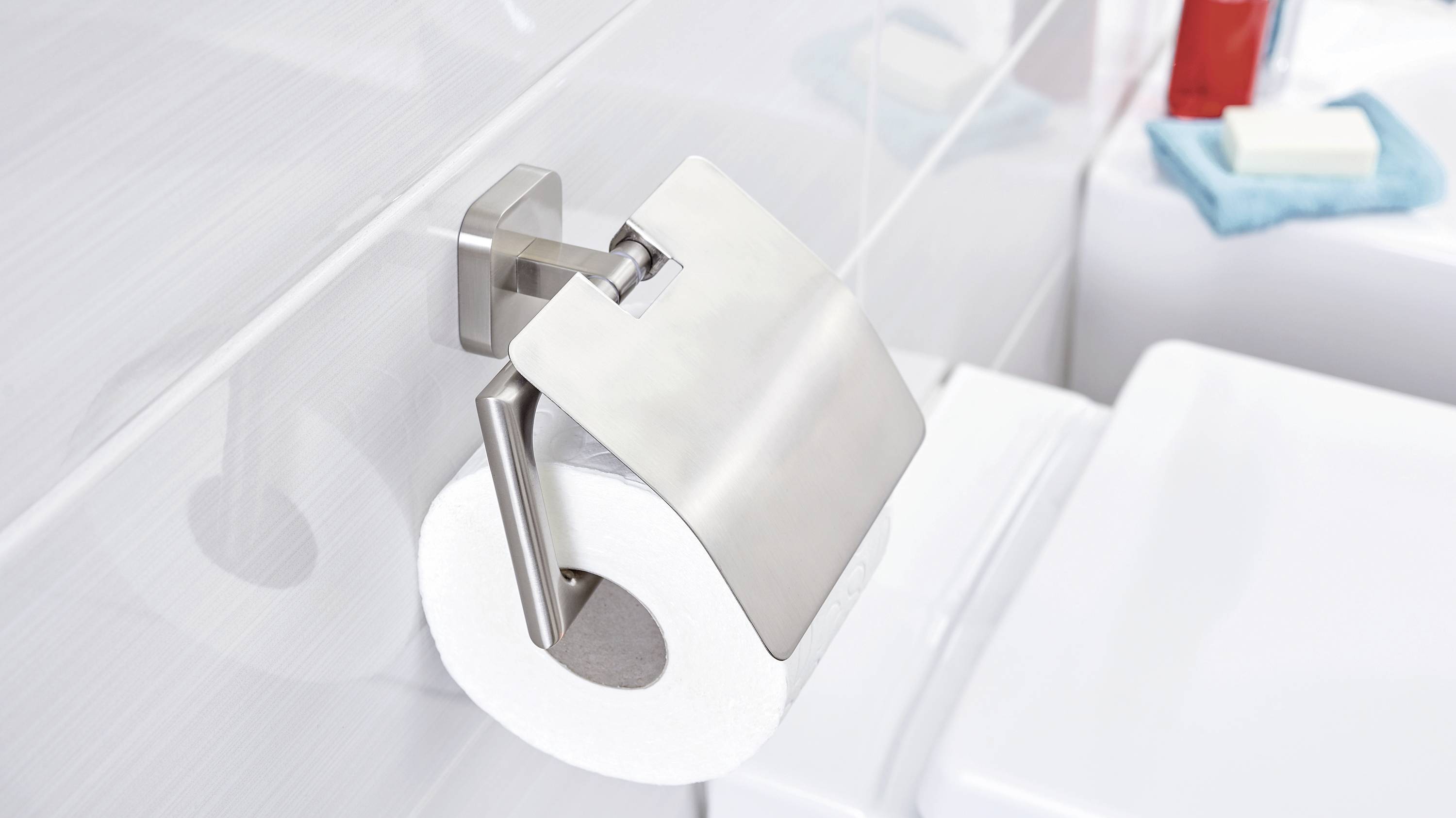 Toilet roll on a metal holder in a modern bathroom. Bathroom accessories are visible in the background.