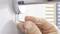 A hand is tightening a screw with an Allen key on a round, metallic wall mount.