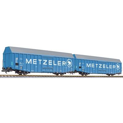 Two blue goods wagons with the inscription 'Metzeler' on their sides, stand on a railway track.