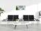 Waiting area with four grey chairs, a table and plants. On the wall, a sign reads 'Welcome to E-Commerce Conference'.