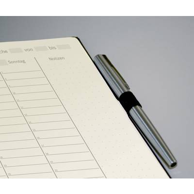 An open notebook is lying on a table. On the left, days and times are listed in a tabular format, and on the right, there is space for notes. A pen is lying beside it.