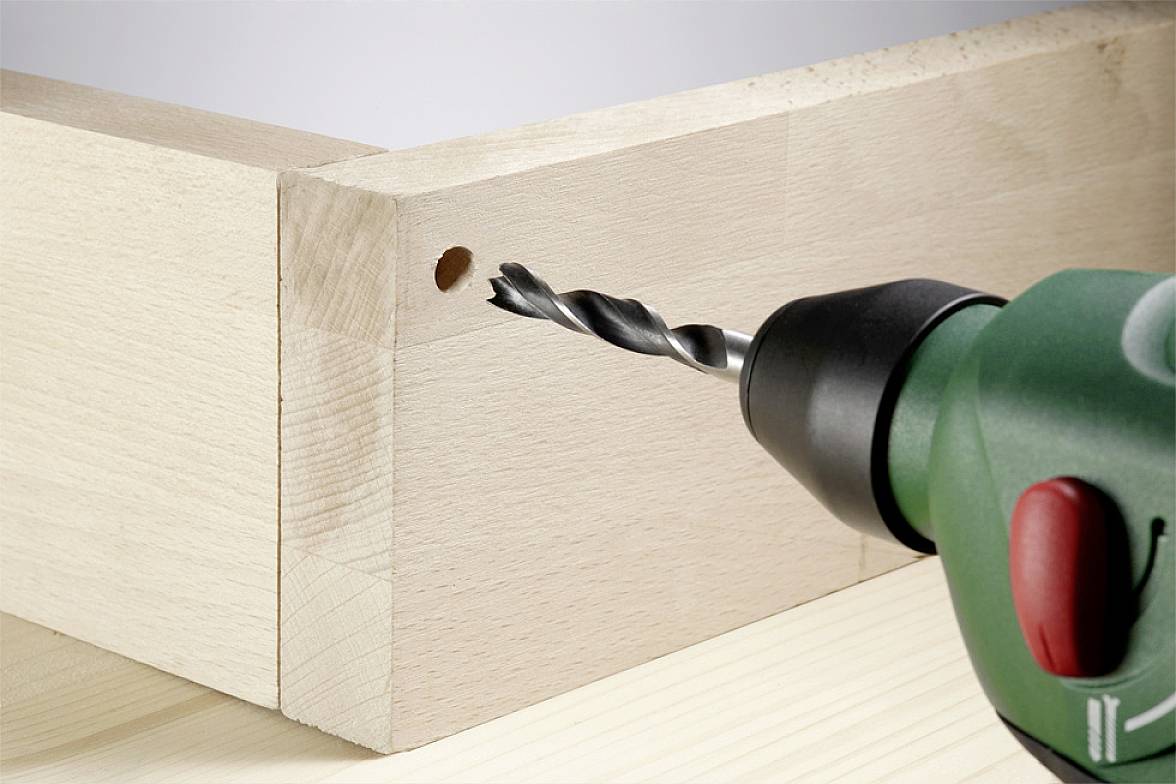Power drill boring a hole into a piece of wood. Close-up shows drill bit in action. Suitable for DIY or construction work.