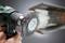 A hand uses a power drill with a wire brush attachment to clean a steel beam, removing rust and debris.