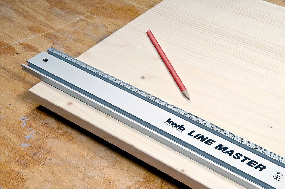 A ruler and a red pencil are lying on light wood. The ruler bears the inscription 'LINE MASTER' and helps with precise measuring.