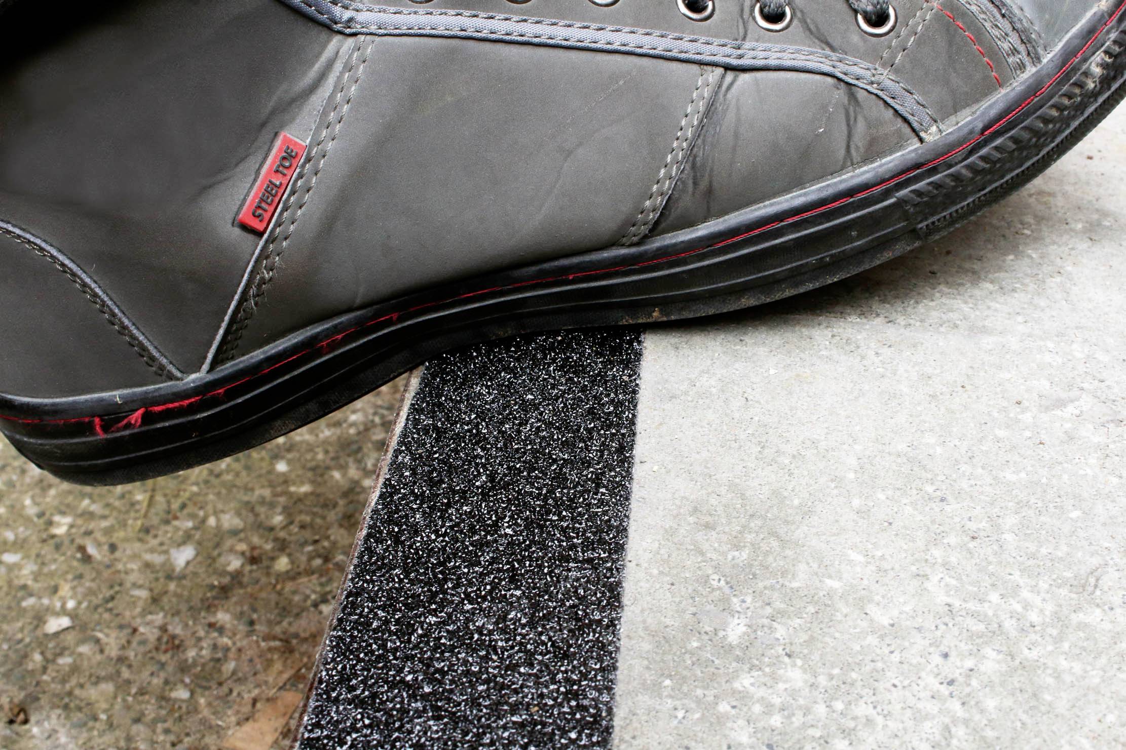 A shoe steps onto a non-slip coated step to demonstrate stability and safety when walking.