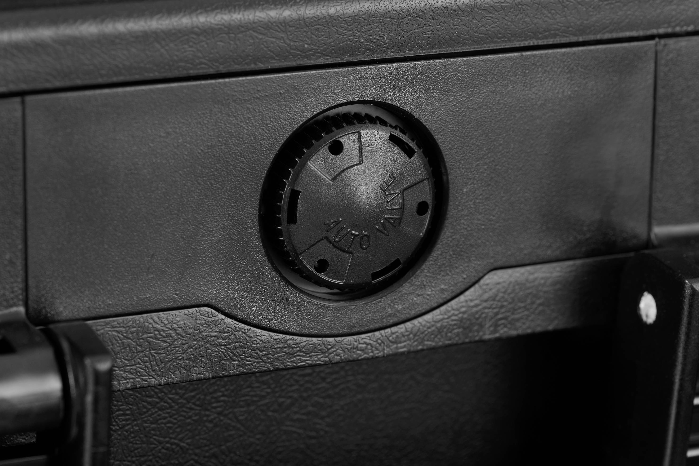 A black round switch on a grey device that allows various settings to be adjusted.