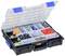 An open plastic organiser with multiple compartments, filled with various screws, wall plugs, and fixing elements.