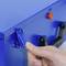 A finger operates the latch of a blue box with a lever handle.
