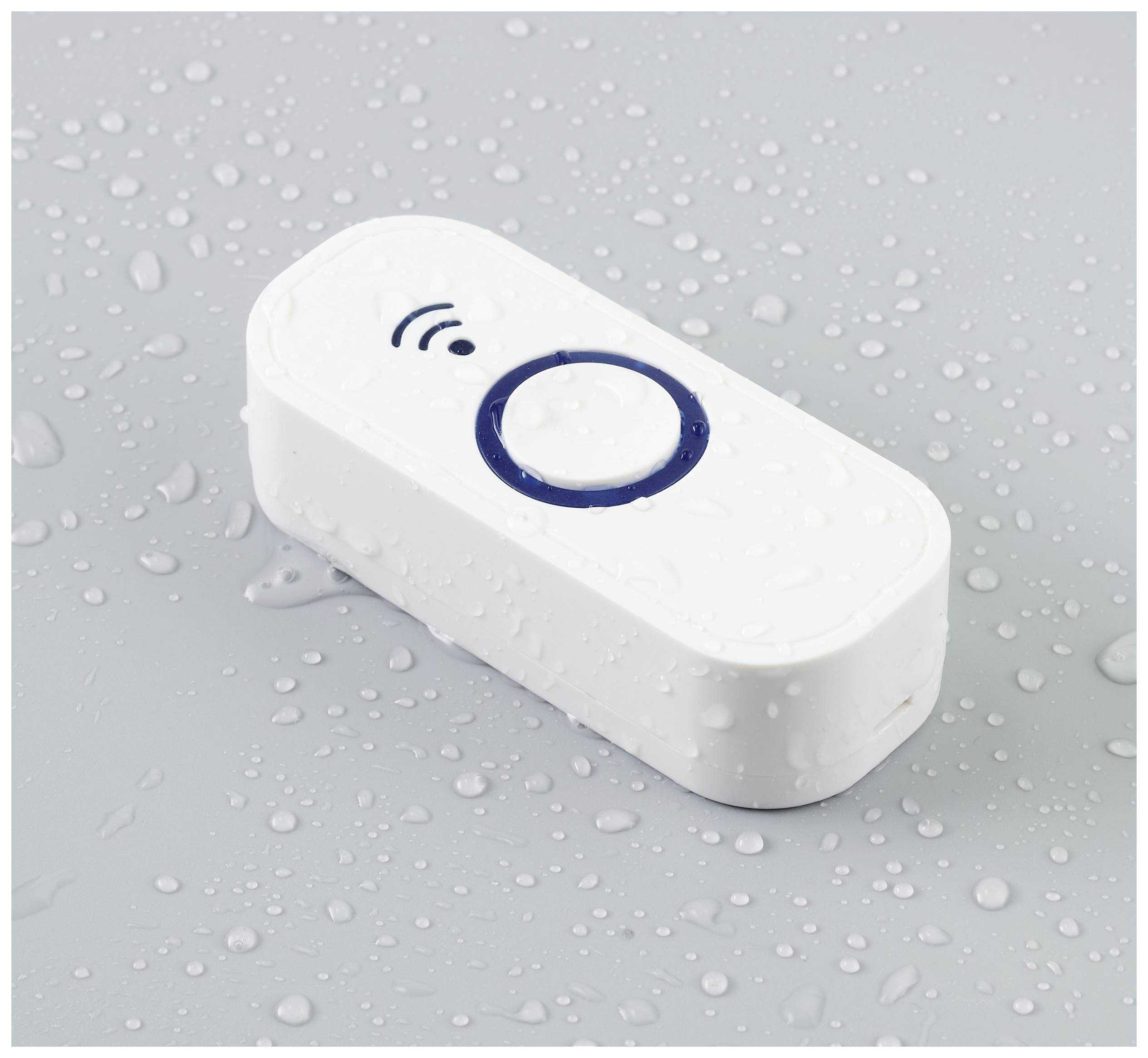 A waterproof, white radio button with a blue circle in the centre sits on a grey surface with water droplets.