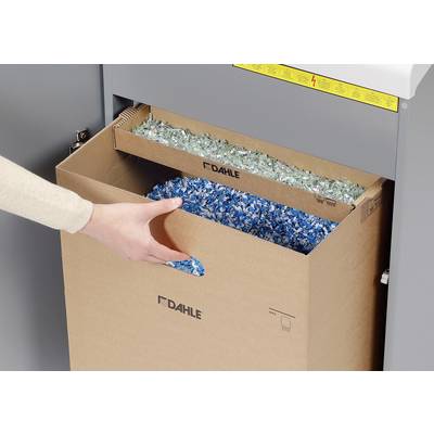 A hand pulls a box out of a shredder. The box is filled with blue and green paper confetti.
