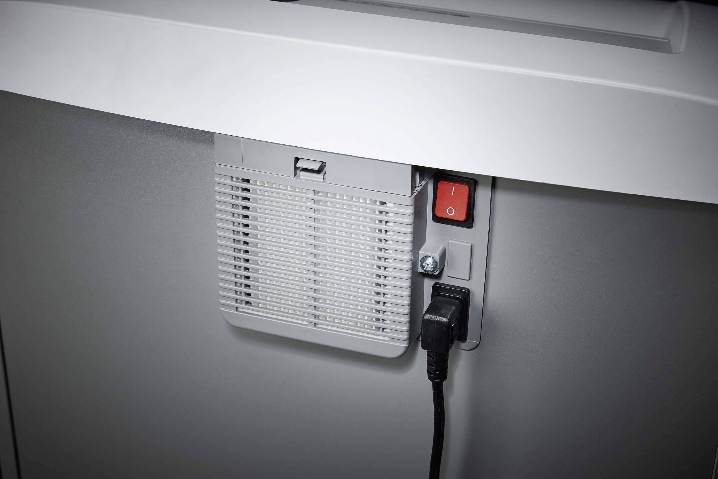 Grey shredder with visible power switch and power cable connection. The waste bin is partially visible.