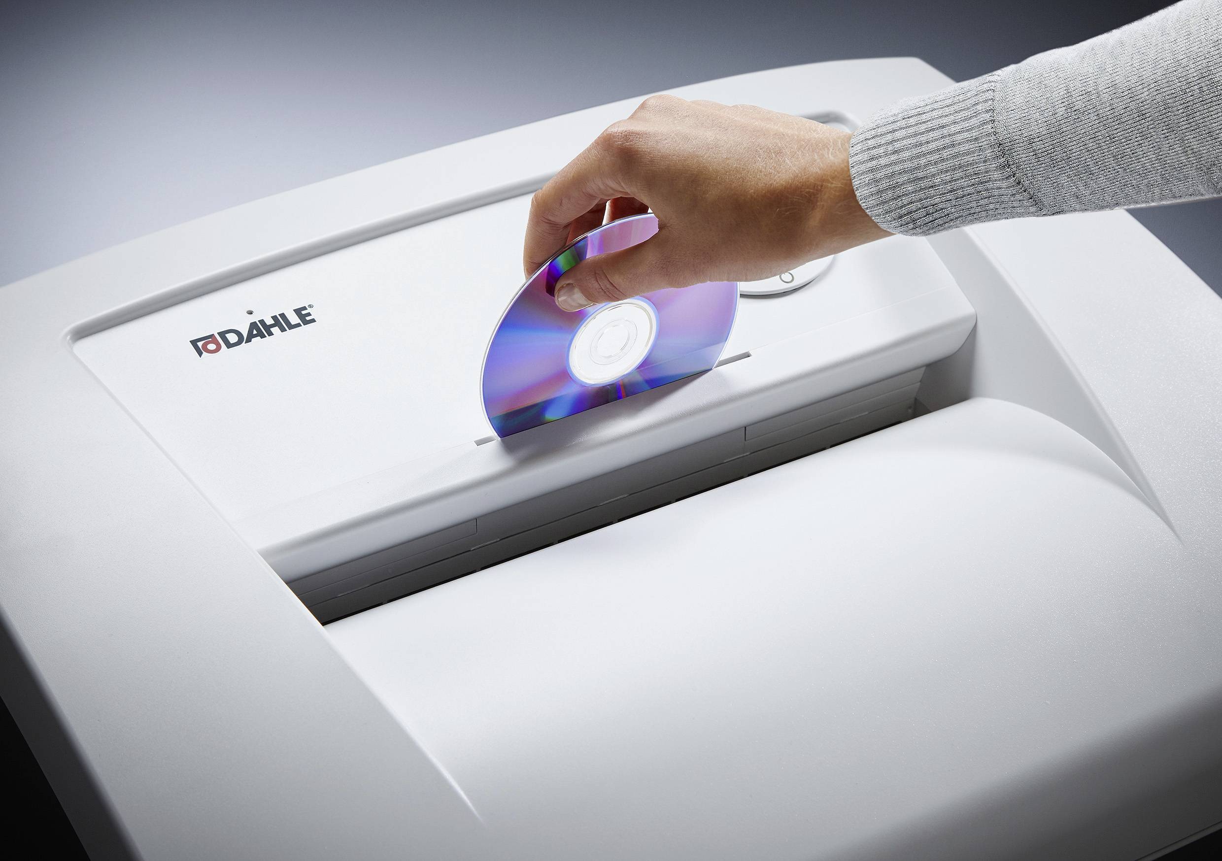 A hand is holding a CD and inserting it into a document shredder made by the company 'Dahle'.