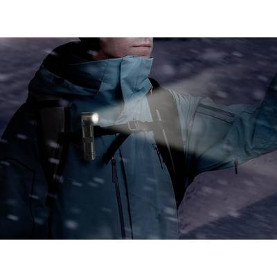 A person in winter clothing is carrying a torch on their shoulder, illuminating the snow.