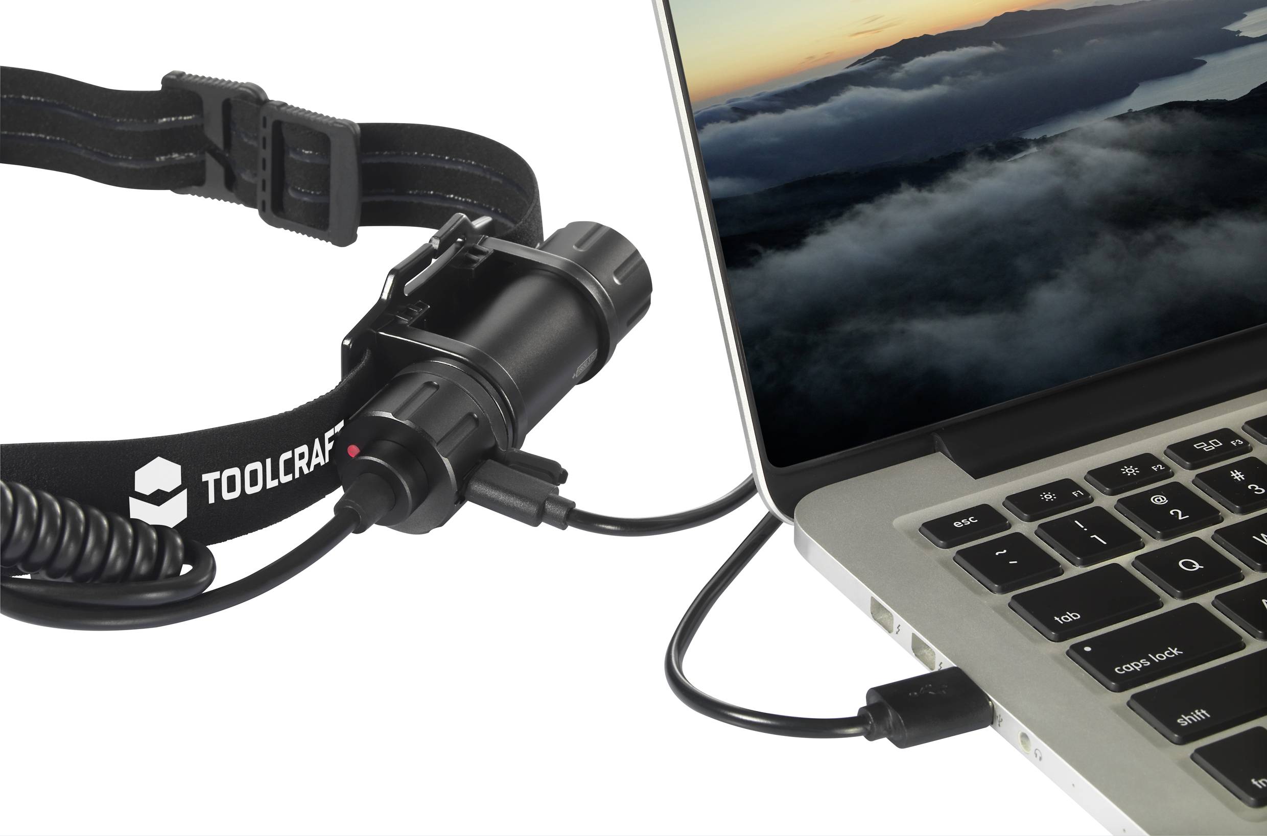 A Toolcraft head torch is connected via cable to a laptop displaying a sunrise over clouds.
