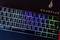 Illuminated gaming keyboard with multi-coloured LED lighting and German layout, background displays 'Surefire' logo.