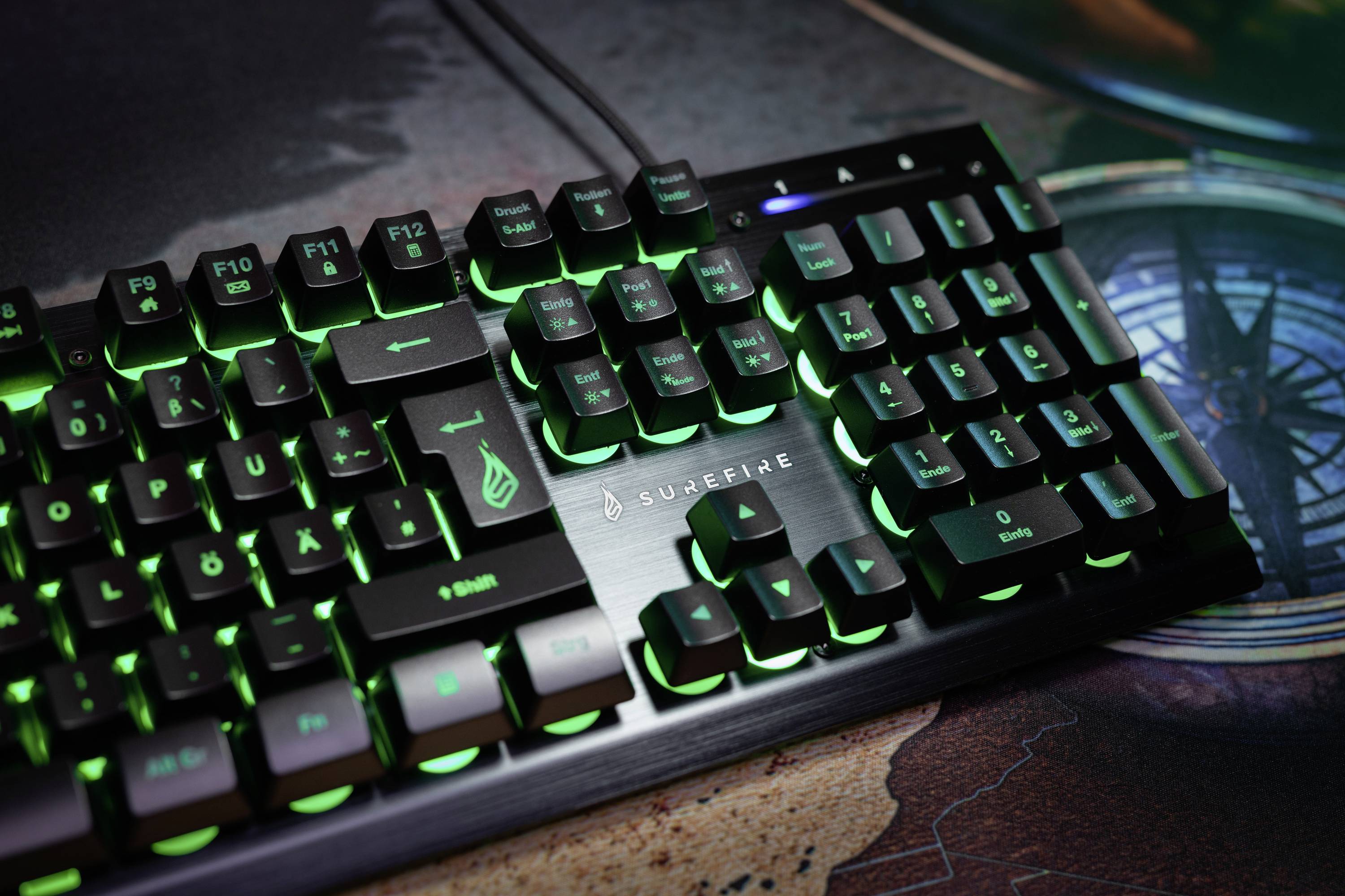 Illuminated mechanical keyboard with green LEDs on a desk. Arrow keys and function keys clearly visible.