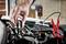 A hand connects a black jump lead to a car battery. A red cable is connected on the right side of the image.