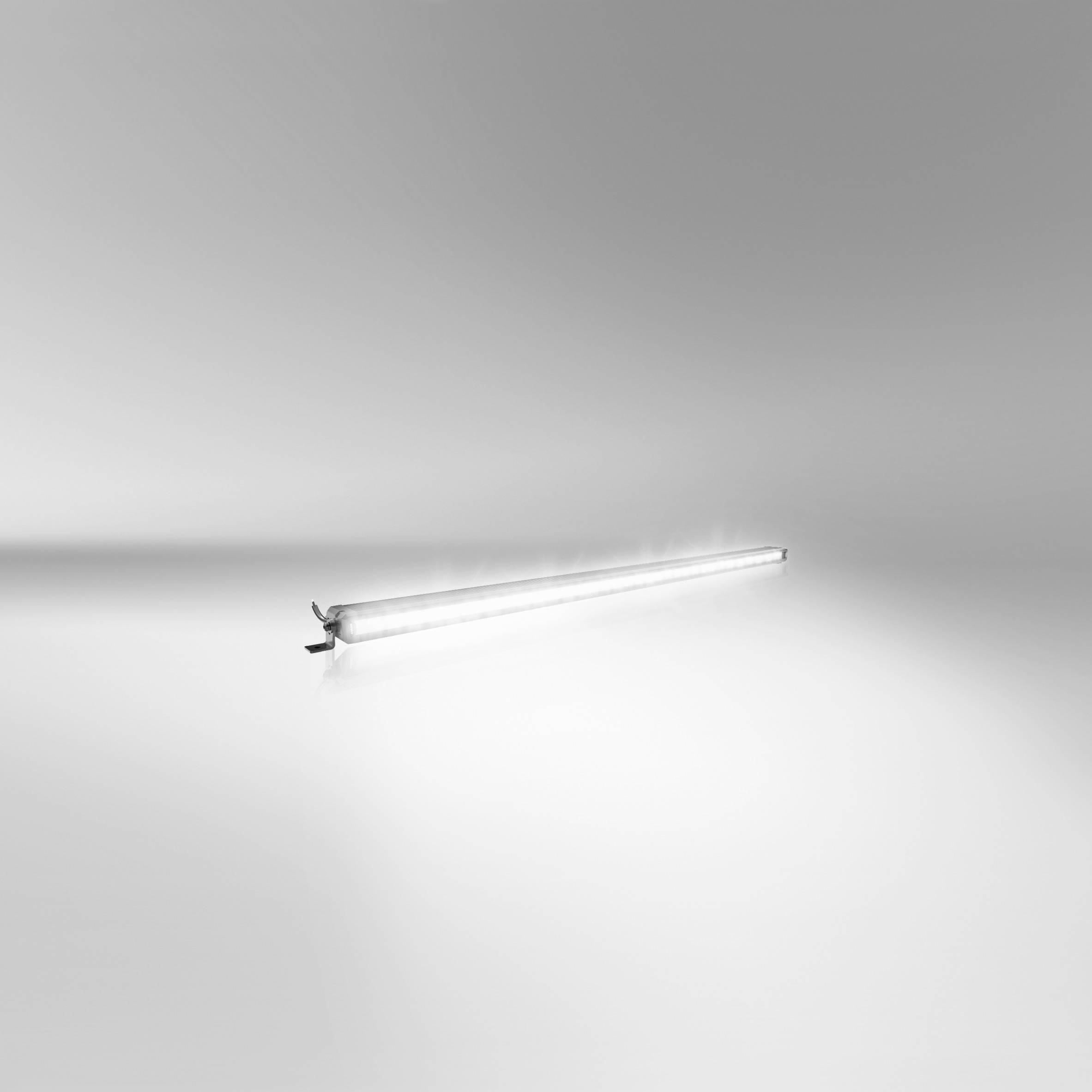 A bright fluorescent tube lying on the floor in an otherwise empty, grey room.