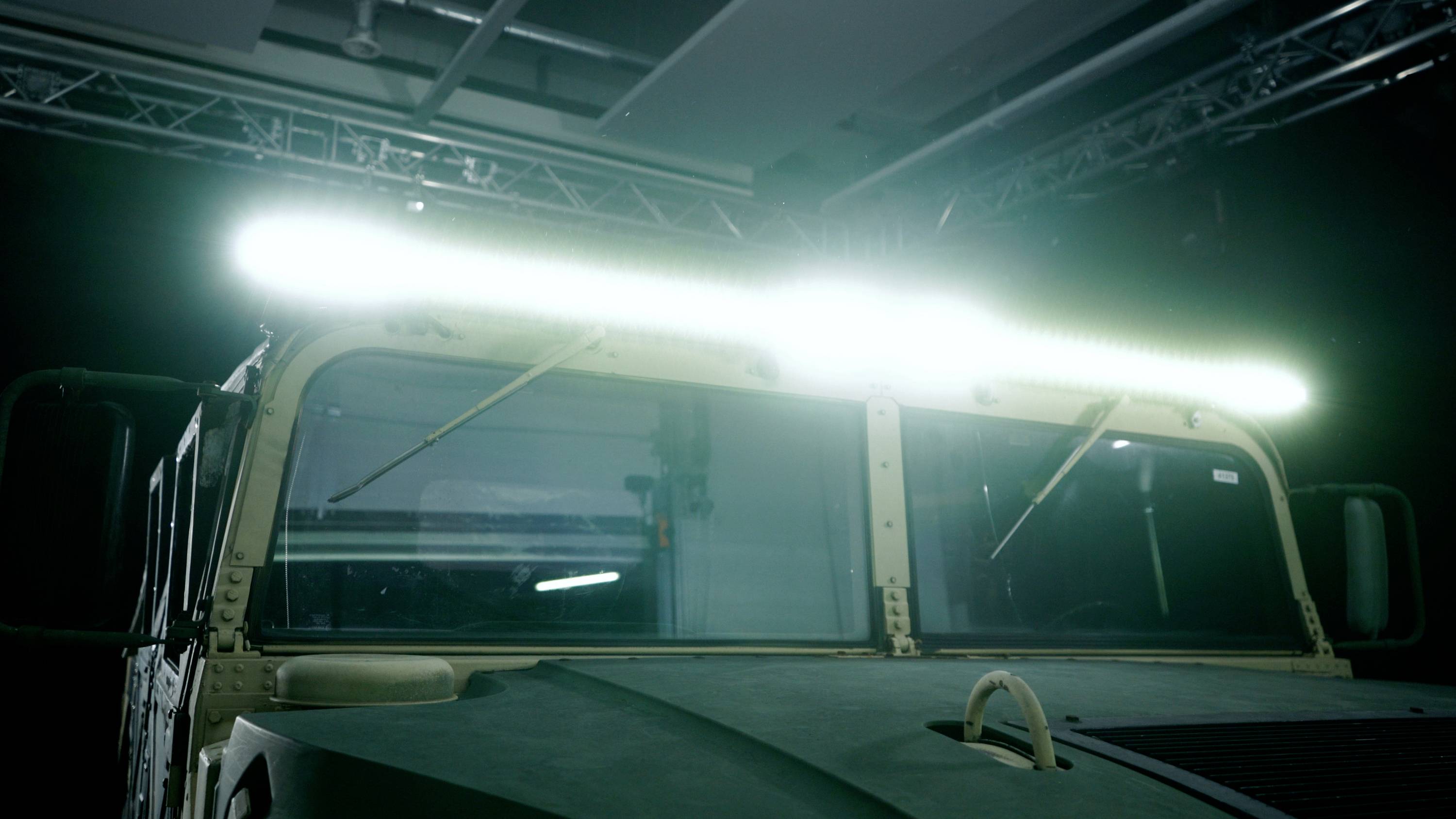 A military vehicle with its light bar activated on the front in a dark room.