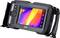 Handheld thermal imaging camera displays a colour infrared image of a technical pipeline on the screen, with several control buttons visible.