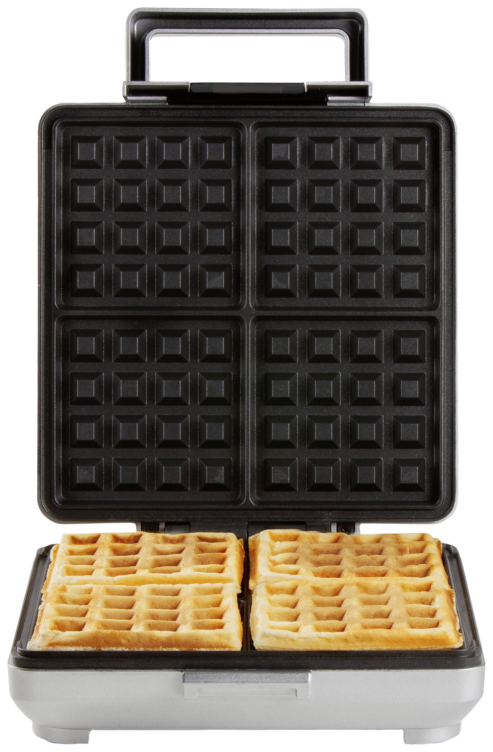 Waffle iron with open lid, two golden-brown, rectangular waffles lying inside.