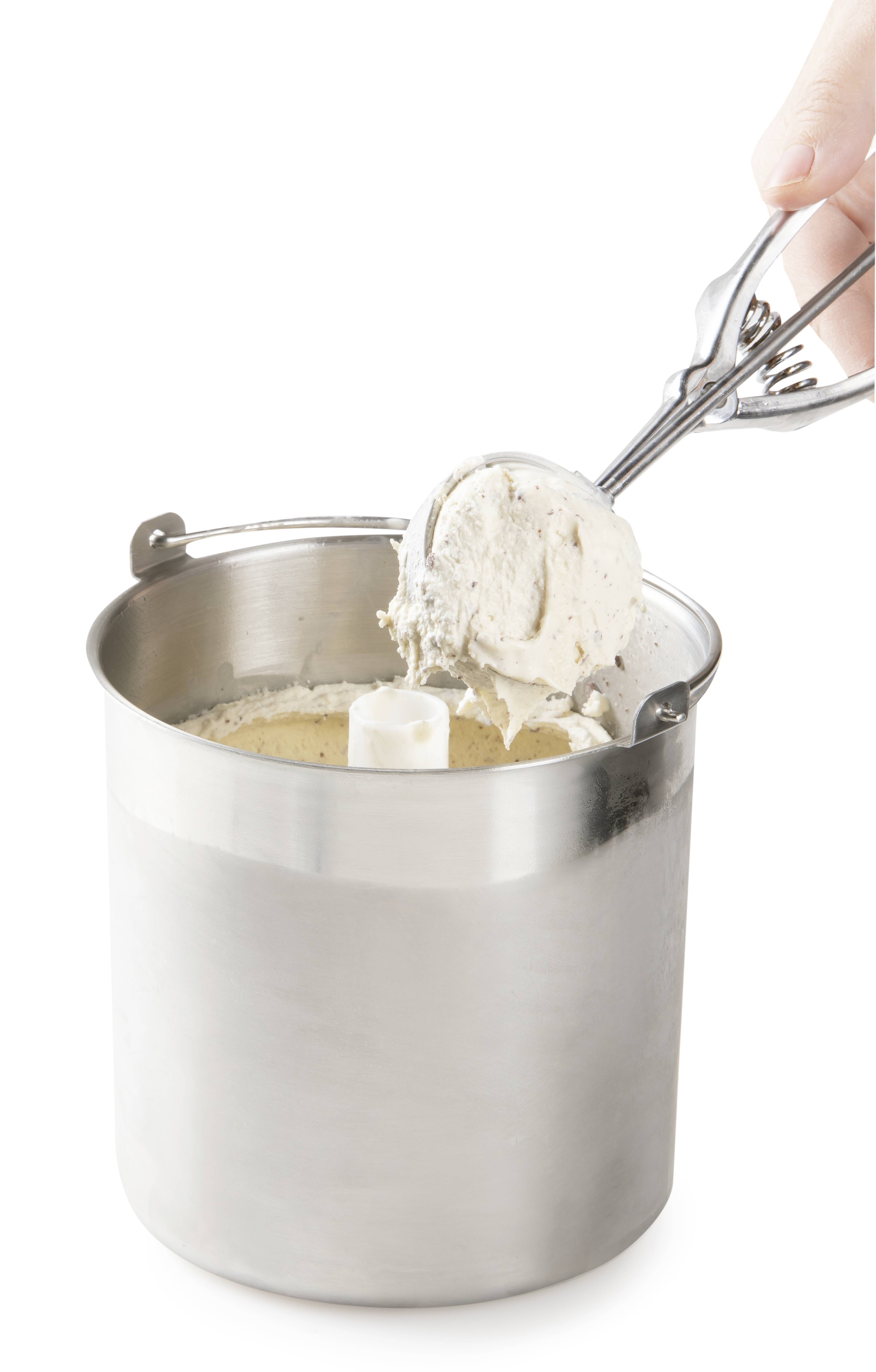 A hand holds an ice cream scoop and scoops vanilla ice cream from a silver metal container.