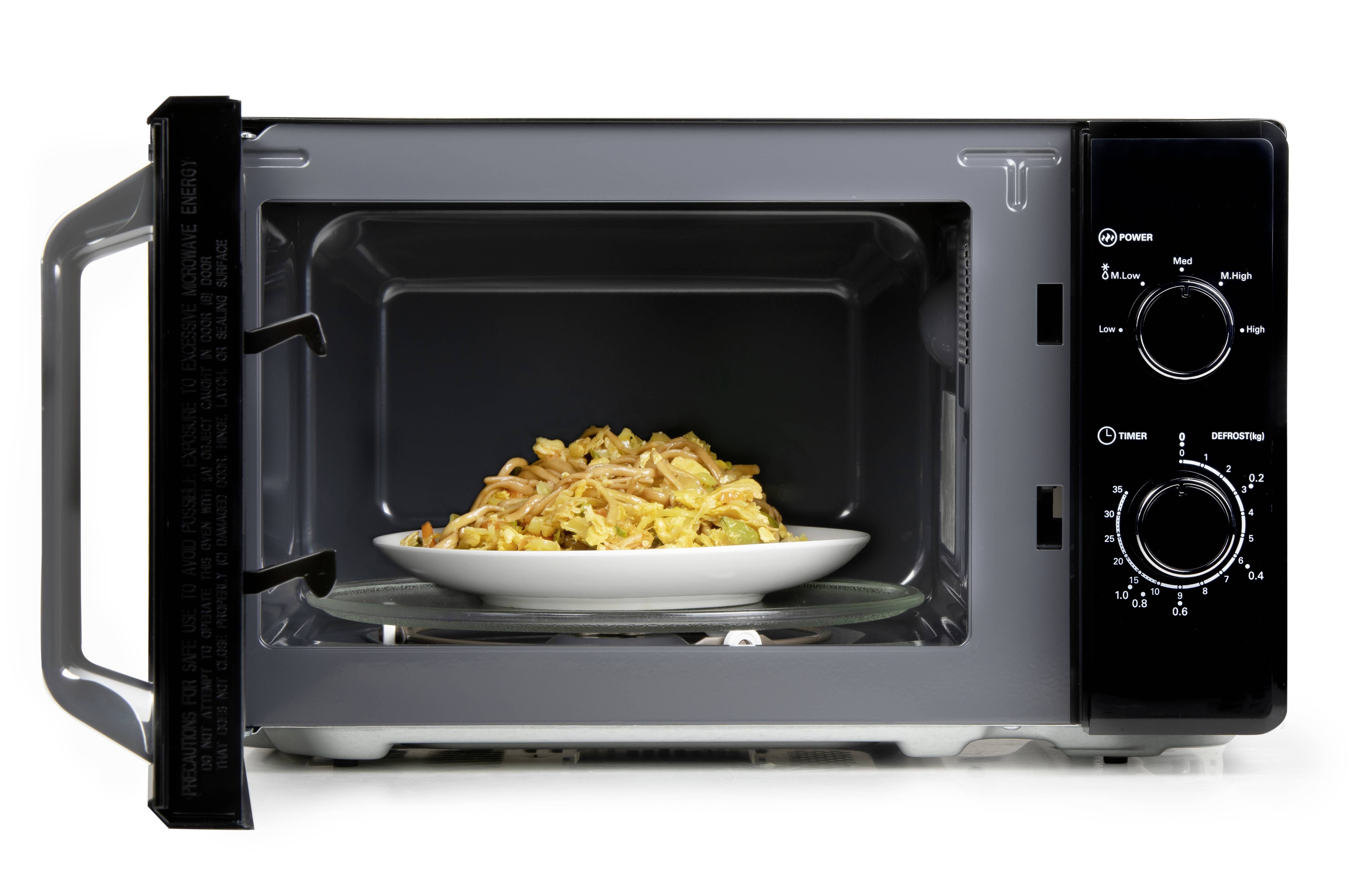 An open microwave shows a plate of cooked pasta inside. The buttons for adjusting time and power are visible.