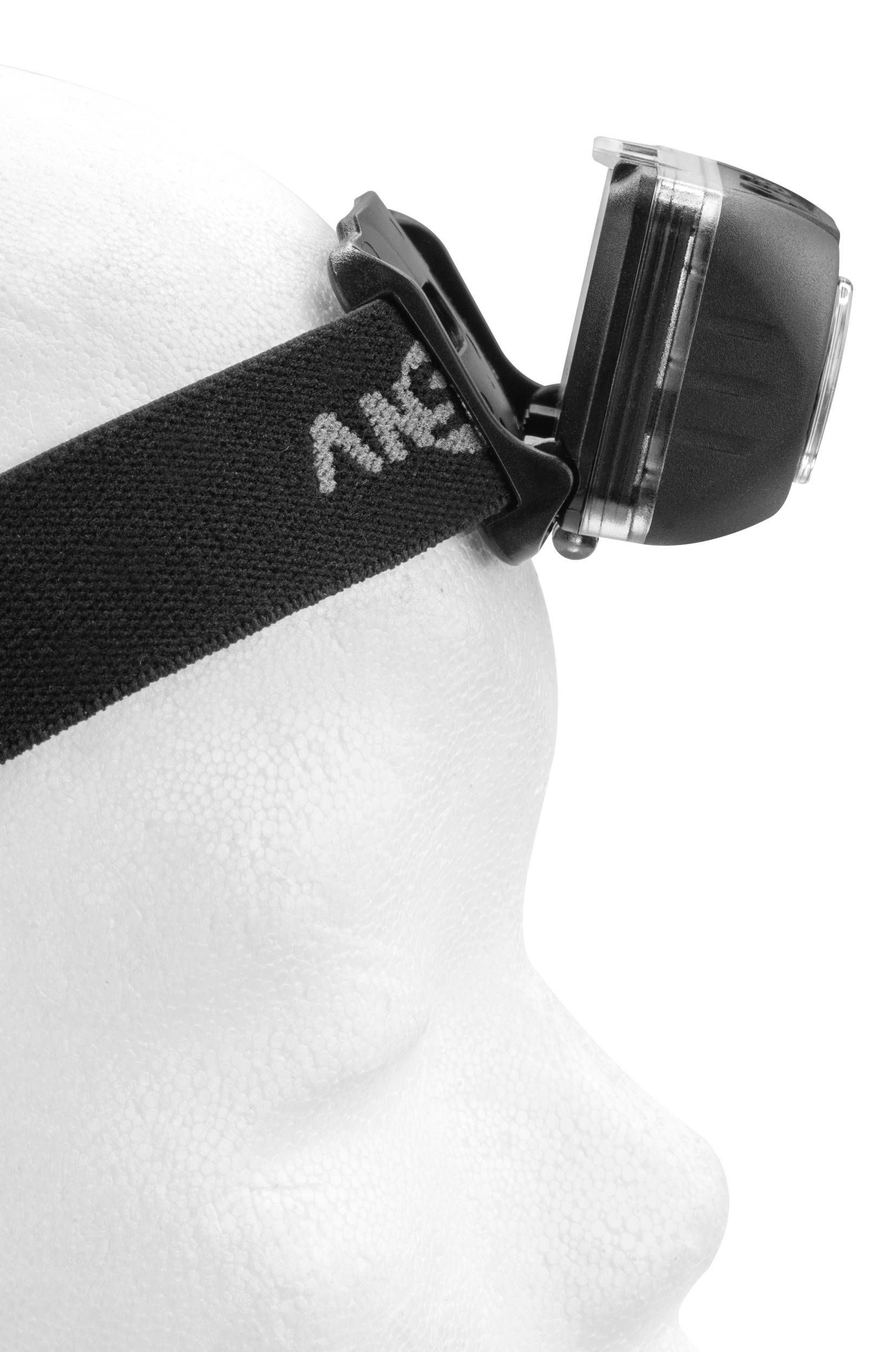 A white model head is wearing a black head torch. The lamp is visible from a side view and attached to an elastic strap.