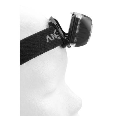 A white model head is wearing a black head torch. The lamp is visible from a side view and attached to an elastic strap.