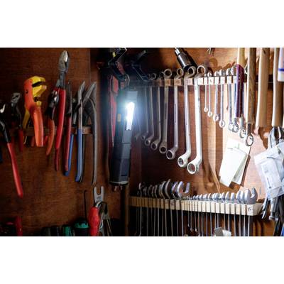 Various tools hang neatly on a wood-panelled wall, including pliers, spanners and a torch.