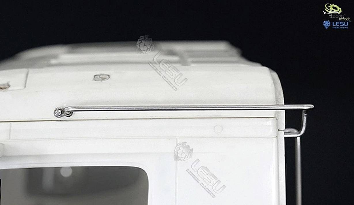 Close-up of a white model lorry cab with a silver metal rail. No further details discernible.