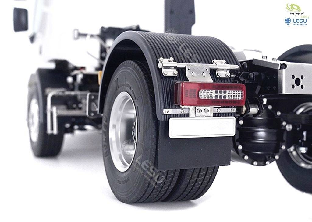 Close-up of a lorry's rear wheel with a detailed view of the wheel arch, rear light, and exhaust system, on a white background.