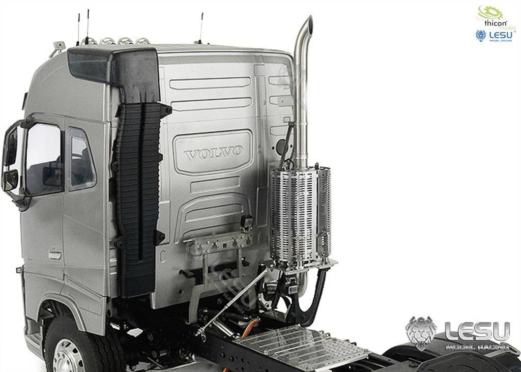 A silver model lorry cab without a trailer. Focus on the design of the cab, including exhaust and manufacturer brand logos.